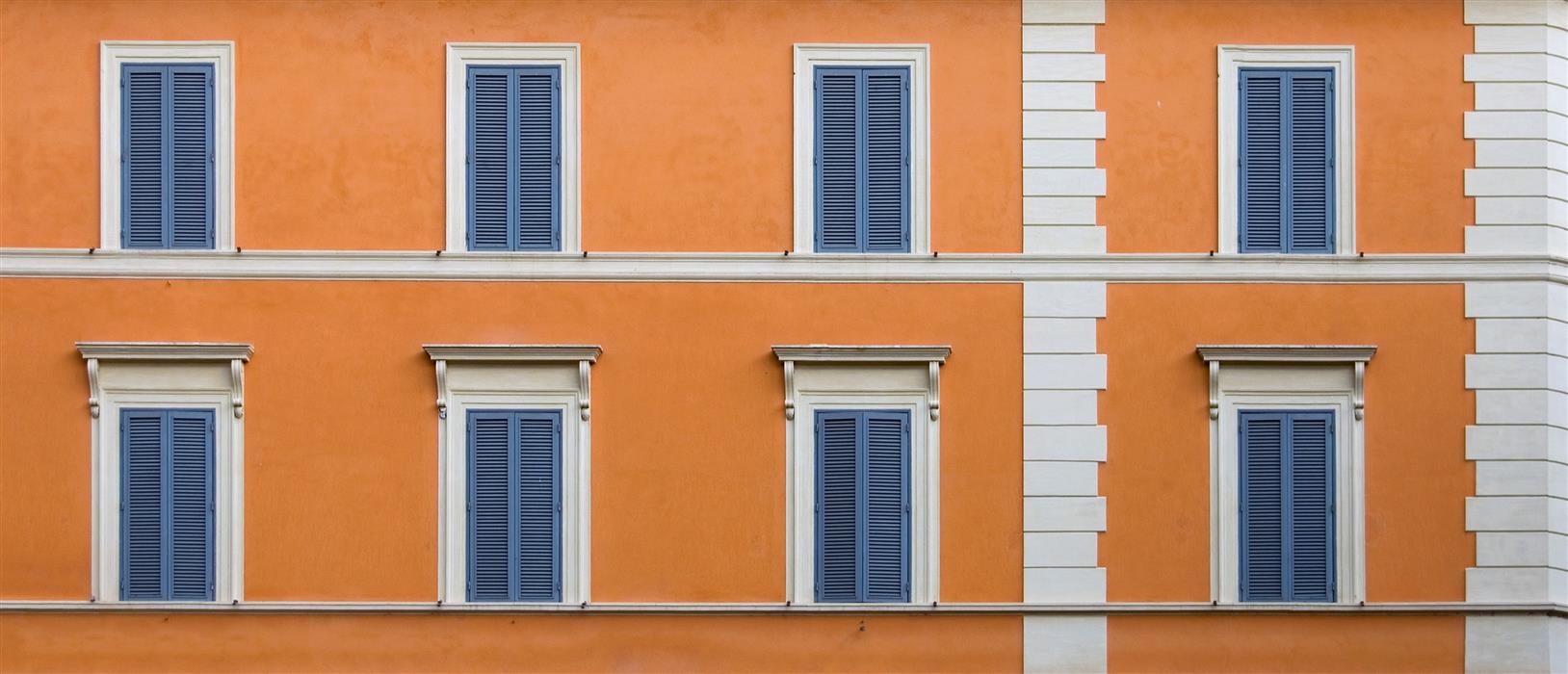 Façade d'immeuble d'habitation rénovée avec de la peinture extérieure dans les tons naturels, bleus et orangés