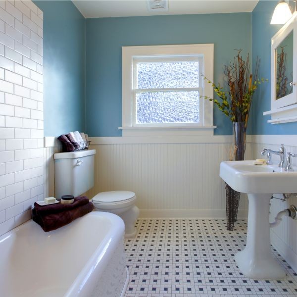 Casa de banho de azulejos com parte da parede pintada de azul